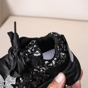 Détail macro de baskets à paillettes pour fillettes avec un grand nœud en satin noir
