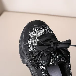 Détails de paillettes noires, papillon en strass argentés et nœud en satin sur la chaussure