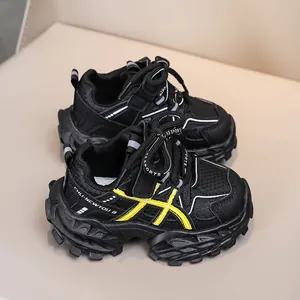 Detail of children's black sneakers with yellow stripes and thick chunky soles