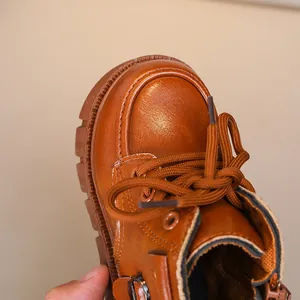 Macro view of brown children's Martin boot showing detailed leather texture and round toe
