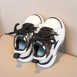 Detail of children's white sneakers featuring thick non-slip soles and black laces