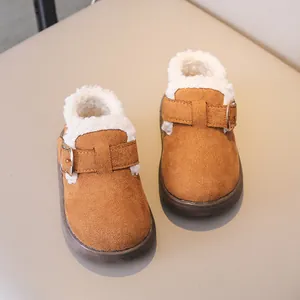 Close-up of children's tan suede boots with thick white faux shearling lining and buckle
