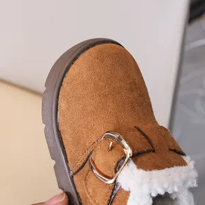 Detail of brown suede kids' winter boots with thick white faux fur lining and gold buckle