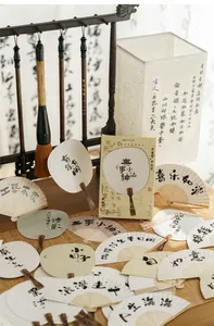 Close-up of Chinese style fan cards with calligraphy and wooden handles on bamboo mat