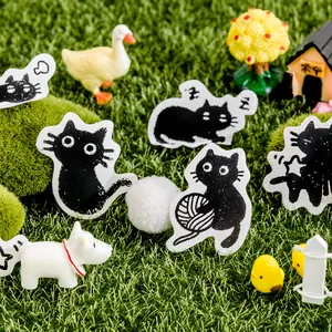 Adesivi gatto nero stile xilografia su una vibrante scena in miniatura di erba verde