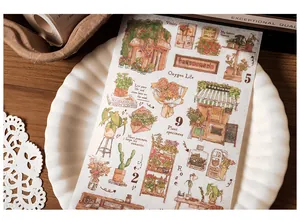 Close-up of vintage hand-drawn floral stickers with plant specimens in a ceramic dish