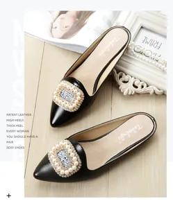 Detail of black patent leather pointed mule shoes with pearl and rhinestone buckle