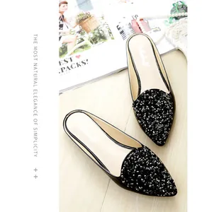 Detalle de mules negros de punta con pedrería brillante y perlas falsas decorativas