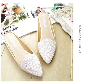 Detalle de mules planos con lentejuelas florales y accesorios de perlas en madera