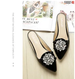 Detail shot of black patent leather pointed toe mule featuring sparkling square rhinestones