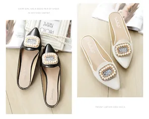 Detail of elegant black and white patent leather pointed mules with pearl and crystal buckle