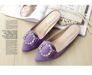 Close-up of purple suede pointed-toe mules featuring sparkling rhinestone buckle and bow