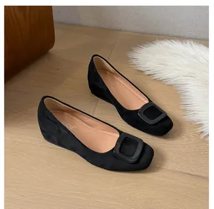 Top view of black suede flat shoes with square toe and large buckle on wooden floor