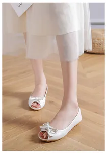 Dettaglio di ballerine bianche spuntate con elegante fiocco su pavimento in legno
