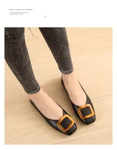 Détail de ballerines noires à bout carré ornées d'une boucle métallique dorée chic