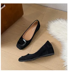 Close-up of black suede flats featuring a square toe and matching buckle detail