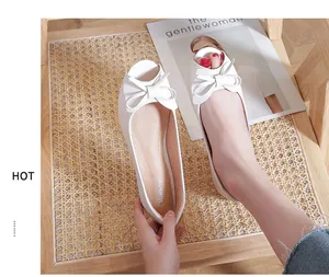 Dettaglio di ballerine bianche spuntate con doppio fiocco e consistenza in pelle