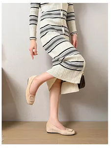 Detail of beige suede flat shoes with a square buckle on a model in a minimalist setting