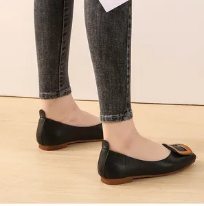 Détail latéral de ballerines en cuir noir avec une boucle carrée décorative en bronze