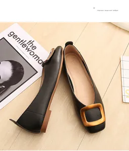 Détail de ballerines noires à bout carré avec grande boucle dorée mate sur bois