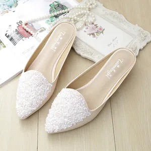 Mules beige de punta con lentejuelas florales en 3D sobre fondo de madera clara