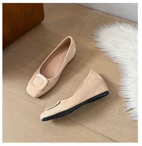 Detailed top view of beige suede ballet flats with a square buckle on wooden floor