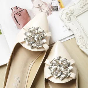 Macro detail of beige patent leather pointed flat shoe with sparkling crystal buckle