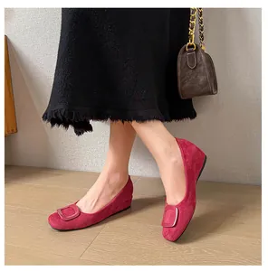 Detailed view of red suede flat shoes featuring a classic square buckle and rounded toe