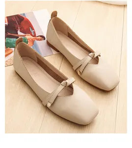 Detailed view of beige square-toe flats with crisscross straps and metal buckles