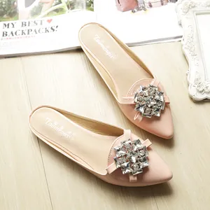 Close-up of pink pointed-toe mule flats with sparkling rhinestone crystal buckles