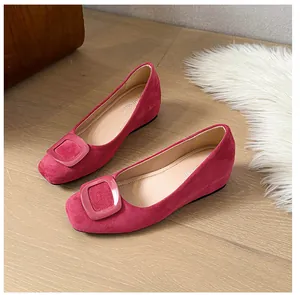 Close-up of pink suede ballet flats with a stylish square buckle on a wooden floor