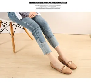 Dettaglio di scarpe Mary Jane beige piatte con cinturino su pavimento in legno