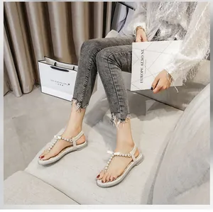 Detail view of T-strap flat sandals featuring elegant pearls and elastic heel straps
