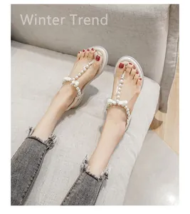 Detail of t-strap flat sandals featuring faux pearls and a white bow decoration