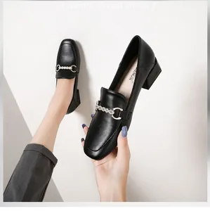 Detail of black loafers with square toe featuring metal chain and pearl embellishments