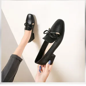 Détail d'un mocassin noir pour femme avec un nœud élégant et une boucle en métal doré