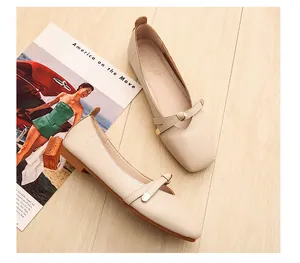 Dettaglio di ballerine beige a punta quadrata con cinturini incrociati su legno