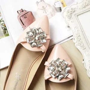 Pink pointed-toe flat sandals with large square crystal buckle decoration on vintage background