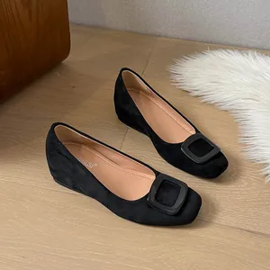Classic black suede ballet flats with square toe and large buckle on wood floor