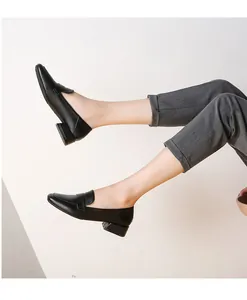 Vista lateral de mocasines negros de mujer con tacón de bloque y pantalones de vestir