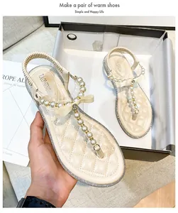 Detail of apricot flip-flop sandal featuring pearl strings, a bow, and quilted footbed