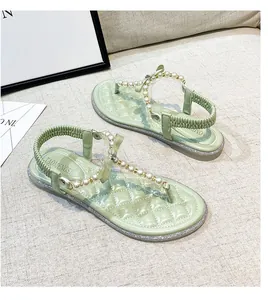 Detail of light green flat sandals featuring pearl straps and quilted insole texture