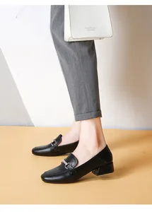 Detail of black leather loafers featuring horsebit buckle with sparkling rhinestones