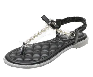 Detail of black thong sandals featuring pearls, a bow, and quilted faux leather insoles