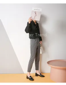 Chic female model styling black loafers with grey high-waist trousers and handbag