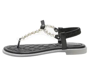 Detail view of black flat thong sandals with white pearls, fabric bow and elastic heel strap