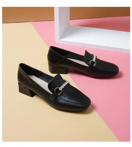 Detail of black leather loafers with metal horsebit buckle and pearl decoration