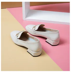Close-up of beige leather loafers with gold horsebit buckle and chunky geometric heel