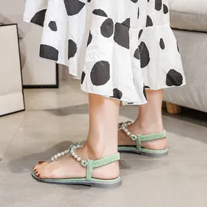 Flat T-strap sandals in light green featuring white pearls and glittery purple rubber soles