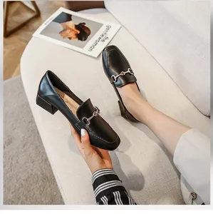 Détail de mocassins en cuir noir à bout carré avec boucle mors dorée et talon épais bloc